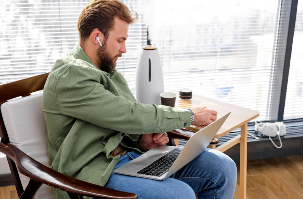 A professional-looking man using his laptop beside a humidifier.