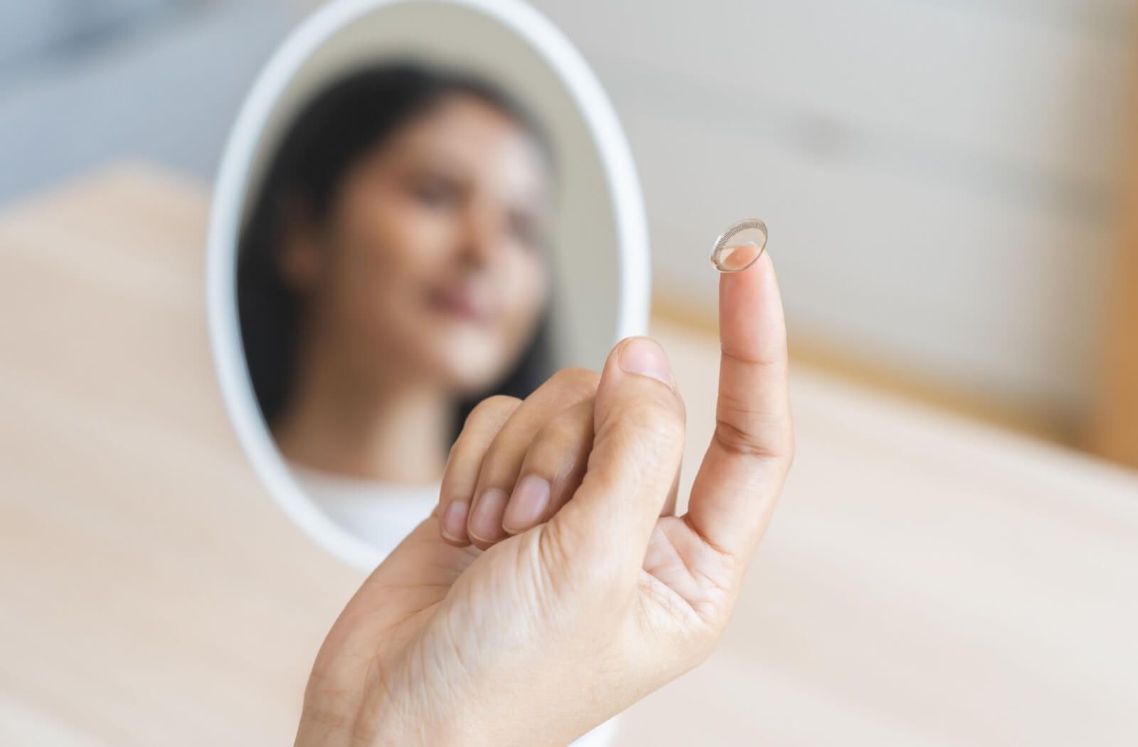 a woman has a contact lens on her index finger ready to place in her eye.