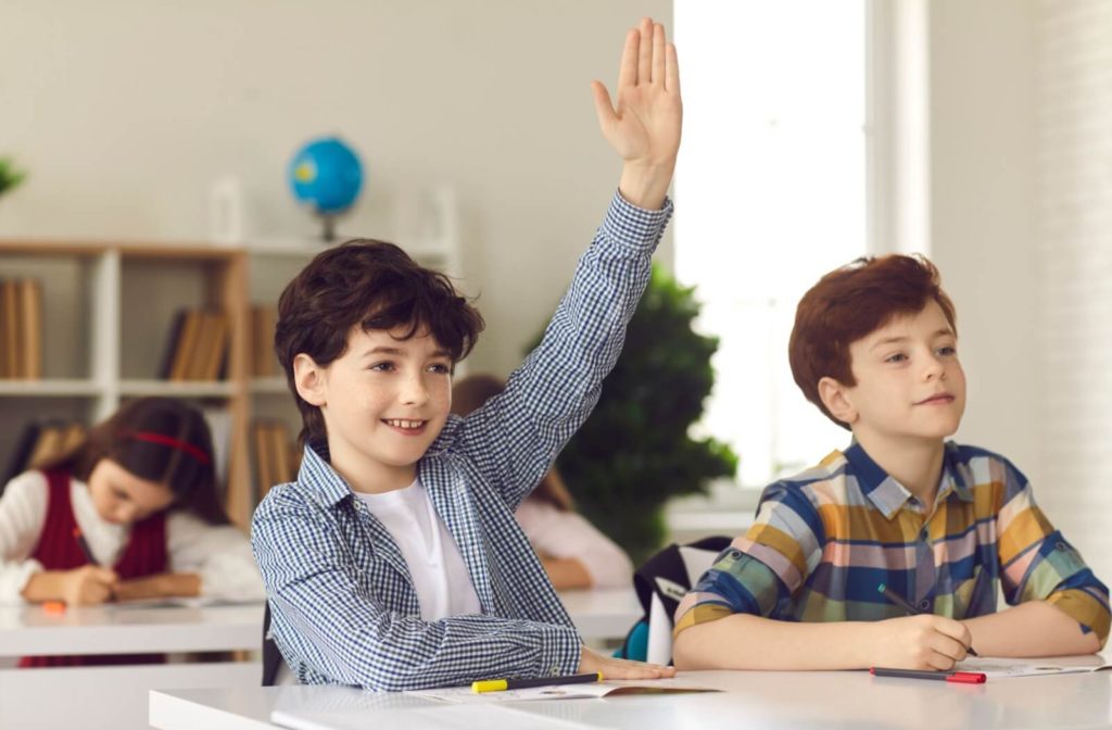 A child raising their hand in class.