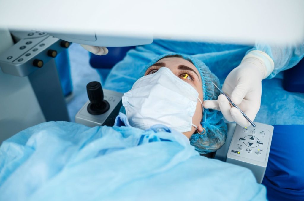 A patient lying on an operating table undergoing LASIK surgery.