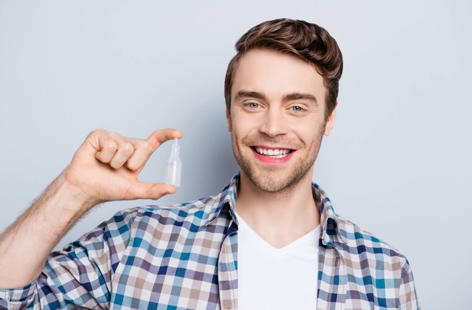 A patient happily holding a bottle of artificial tears.