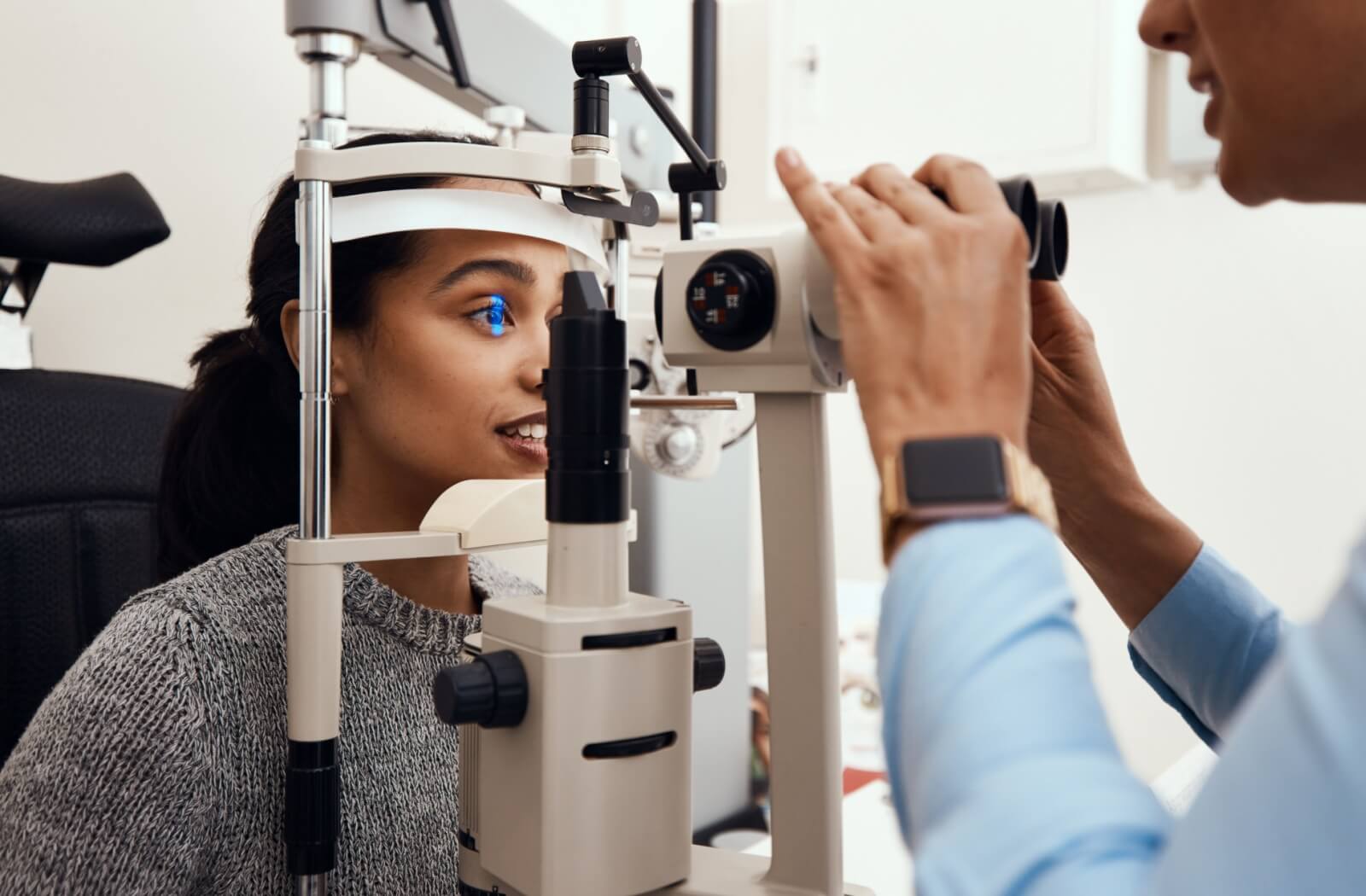 An optometrist uses a slit lamp machine to examine a patient's eyes.