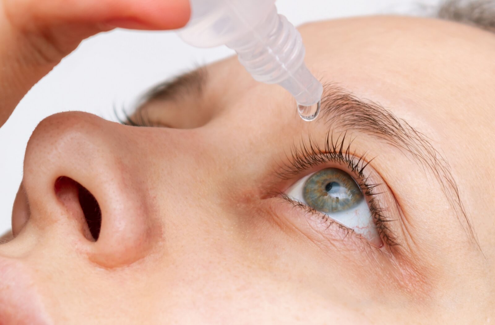Someone putting eye drops in their eyes.