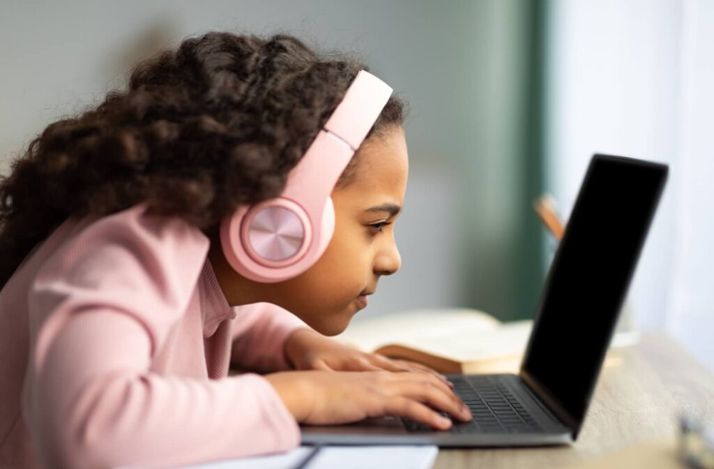 Child leaning close to laptop, struggling to see screen.